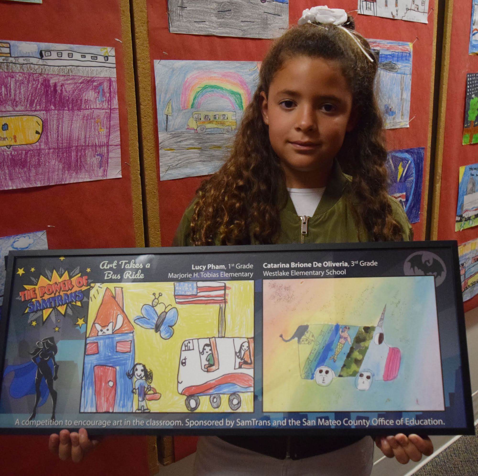 A student shows off her artwork submitted to the Art Takes a Bus Ride competition.
